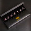 A set of six pink and black resin polyhedral dice displayed inside a dark box labeled Mini Planet