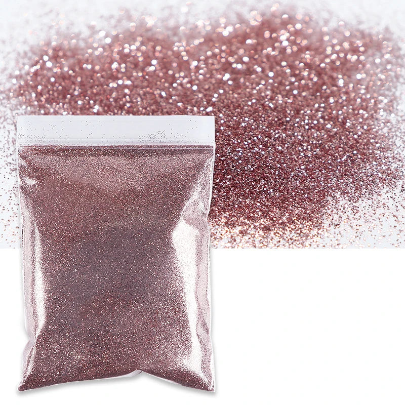 A package of fine holographic glitter powder in a rose gold color next to a loose pile of the same glitter.