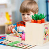 A toddler is interacting with a wooden Montessori toy set featuring orange plastic fruits in a light wood box.
