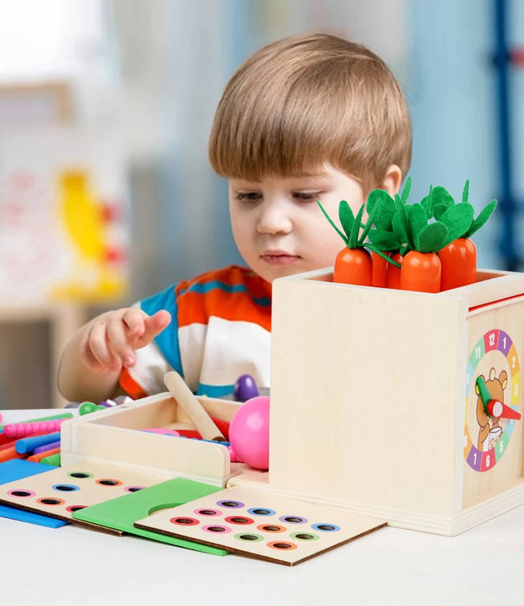 A toddler is interacting with a wooden Montessori toy set featuring orange plastic fruits in a light wood box.
