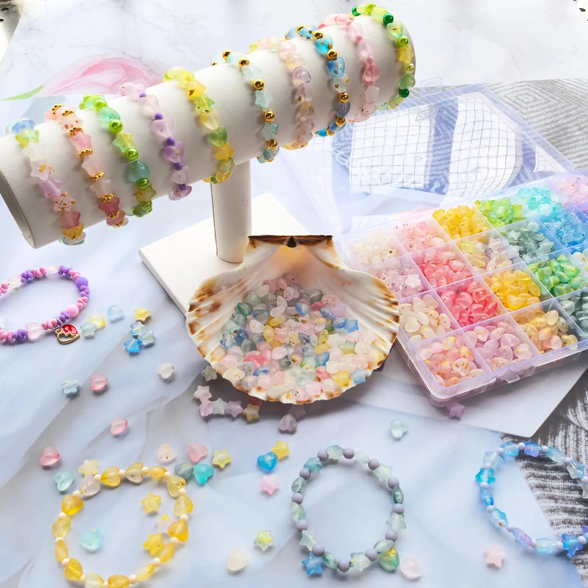 A display of various colored frosted golden foil acrylic beads and a seashell used for DIY jewelry making
