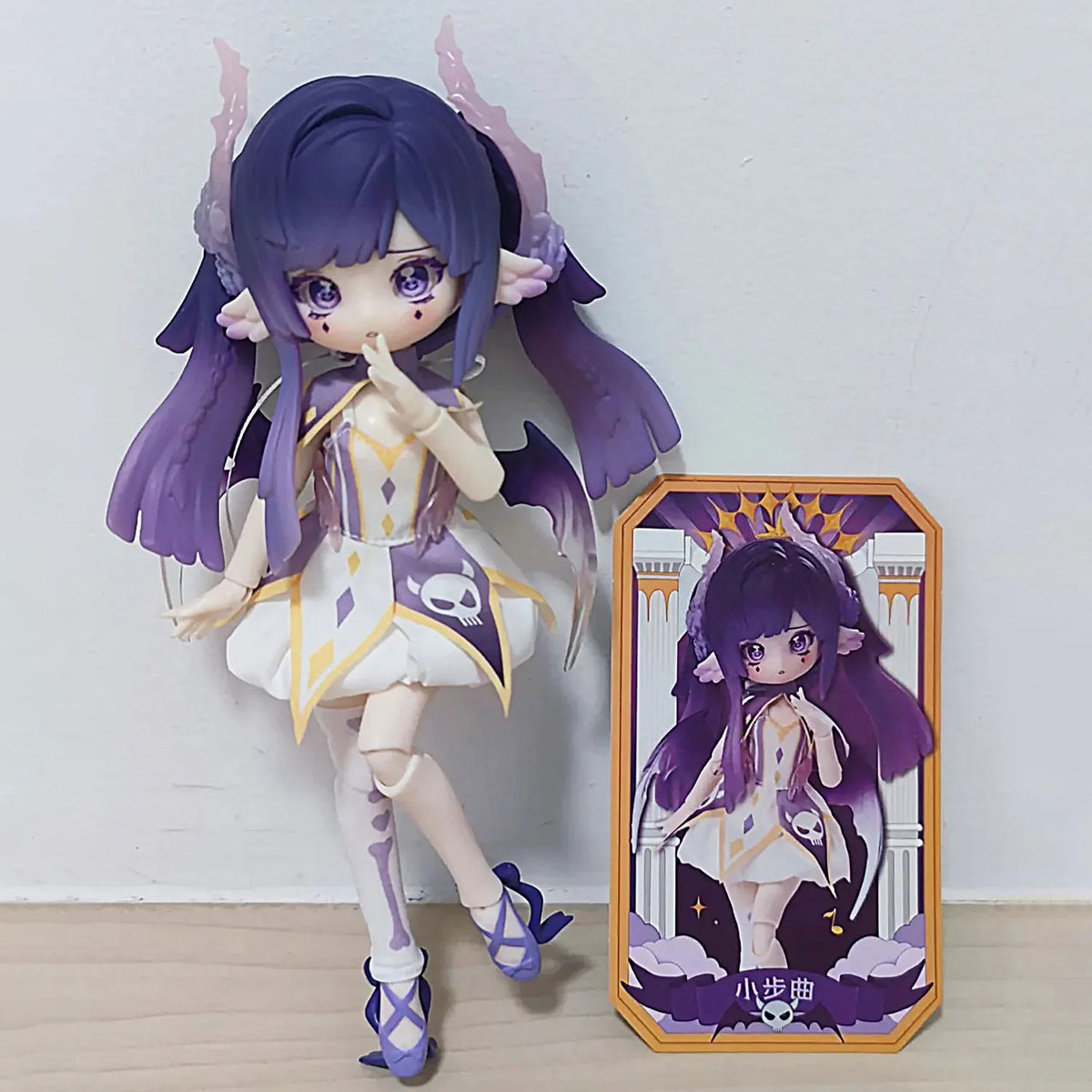 A purple-haired Ball-Jointed Doll (BJD) collectible featuring elaborate wings and white and gold attire.