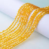 A close-up of yellow faceted glass crystal beads strung together on a white surface.