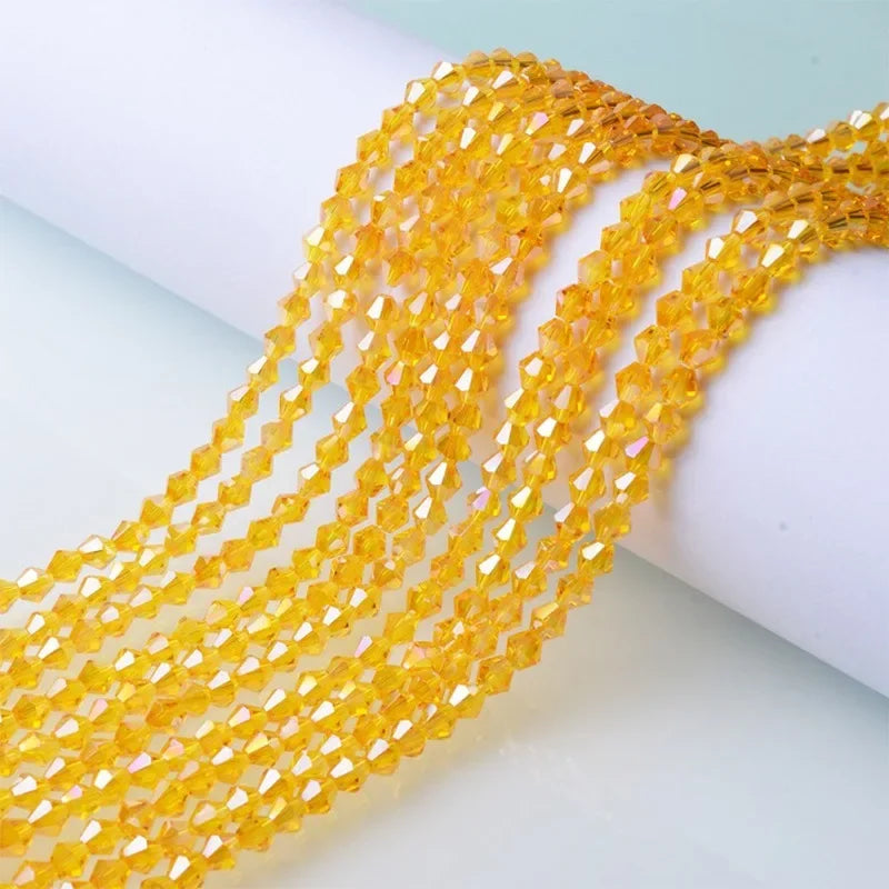 A close-up of yellow faceted glass crystal beads strung together on a white surface.