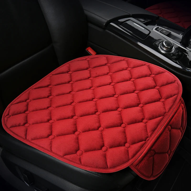 A red quilted car seat cushion set with a black trim is shown in a vehicle interior.