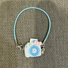 A light blue beaded necklace with a small camera charm and pink bow, suitable for a Labubu doll.