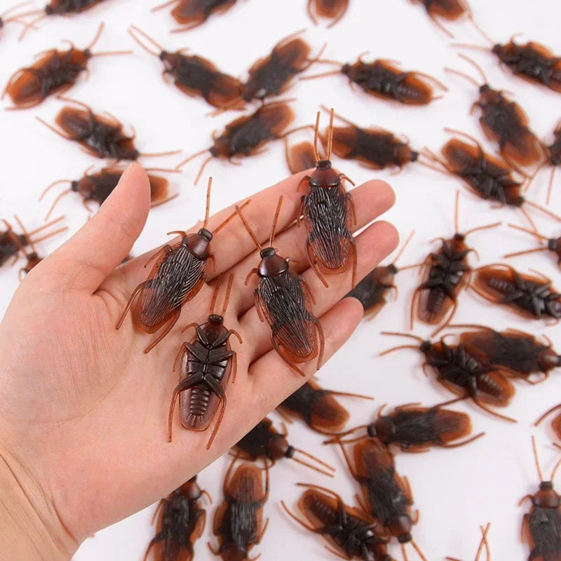 A hand holds numerous lifelike fake cockroaches for props and Halloween