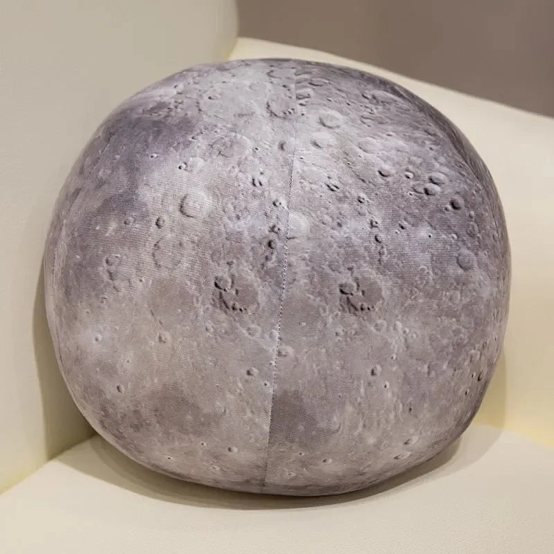 A spherical plush toy resembling the moon, gray in color, displayed in a white box.