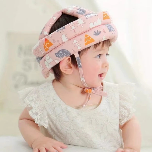 A baby wearing a pink safety hat designed to help them learn to walk.