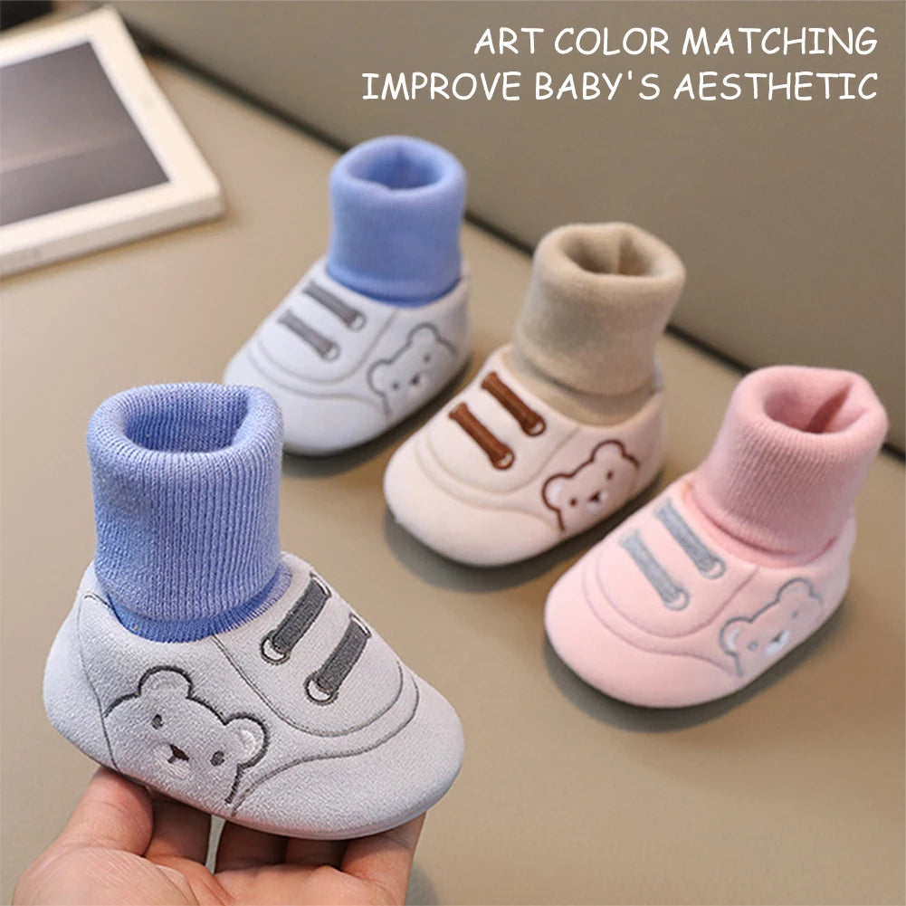 A hand holds a pair of soft baby shoes with anti-slip TPR soles in various pastel colors like blue, beige, and pink.