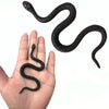 A black rubber snake prop is shown coiled and writhing on a person's hand.
