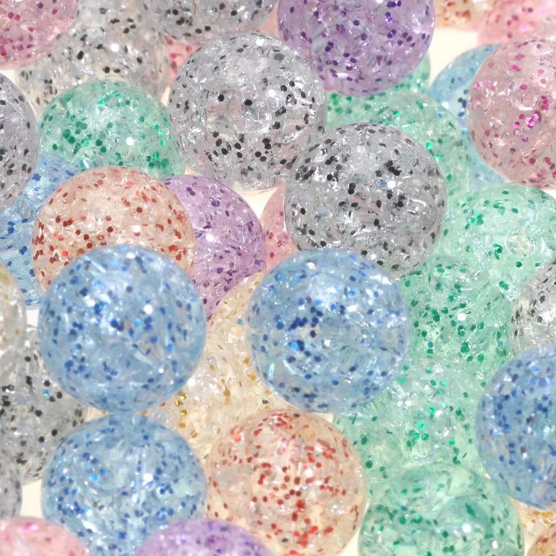 A close-up view of various round glitter cracked acrylic beads in shades of purple, pink, blue, and green.