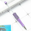 A purple beaded ballpoint pen craft kit with a silver tip rests on a white surface next to a book.