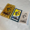 A deck of bilingual golden foil tarot cards titled The Fool, featuring an illustration of a figure walking on a rocky landsca