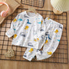 White cotton pajama set for kids featuring a pattern of blue and yellow birds and animals on a black grid.