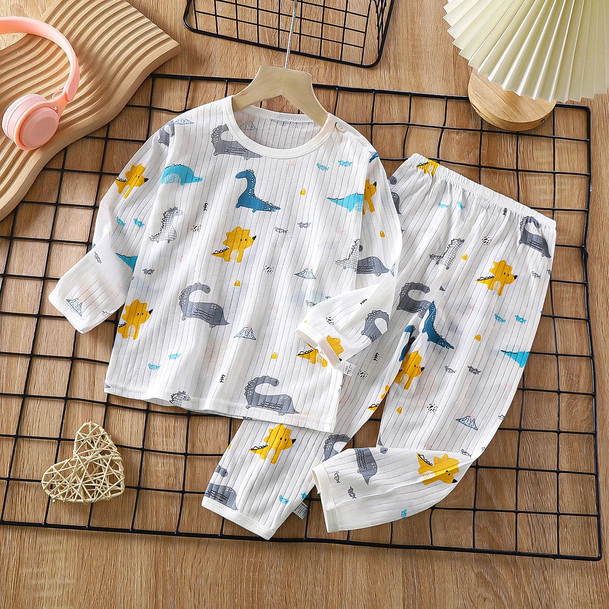 White cotton pajama set for kids featuring a pattern of blue and yellow birds and animals on a black grid.