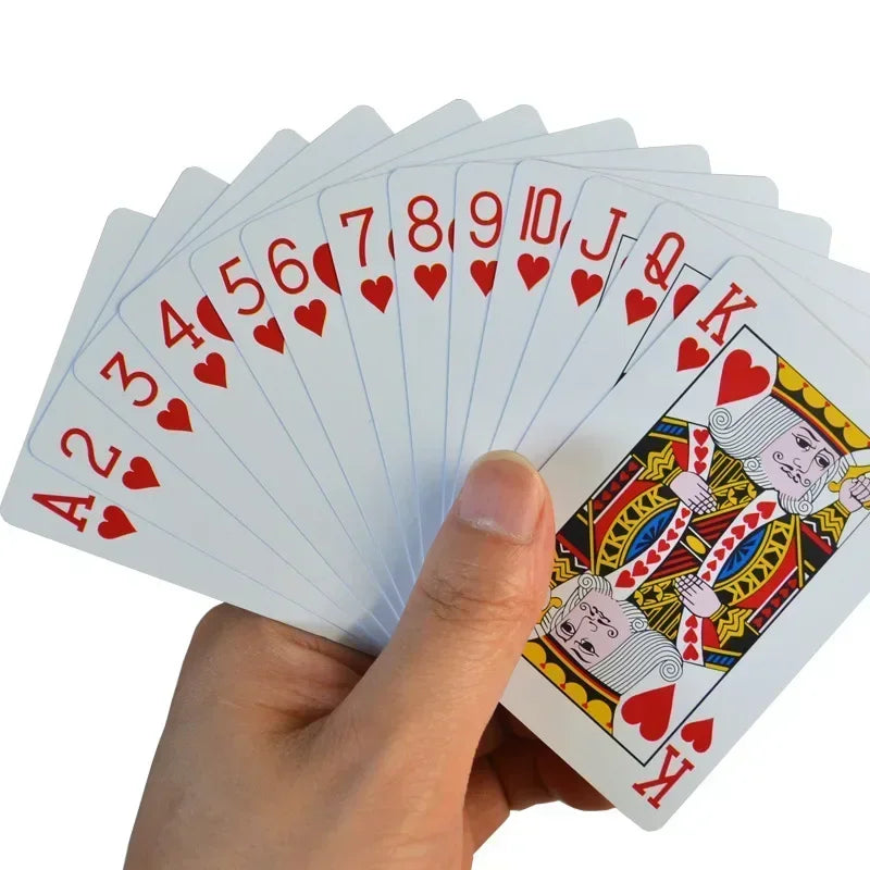 A hand holds a fan of waterproof plastic playing cards showing the Ace through King in red suit.