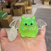 A bright green, translucent squeeze stress relief ball shaped like a bat with wings is held in a hand.