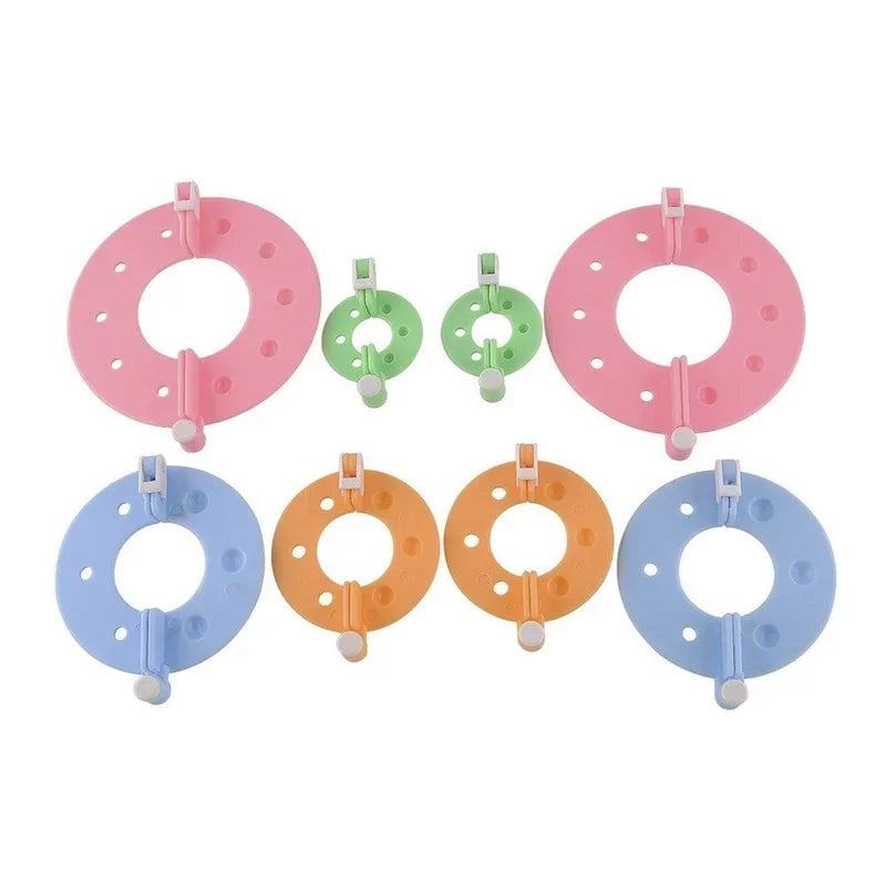 An assortment of eight pink and green pom pom maker rings and tools for DIY knitting and craft projects