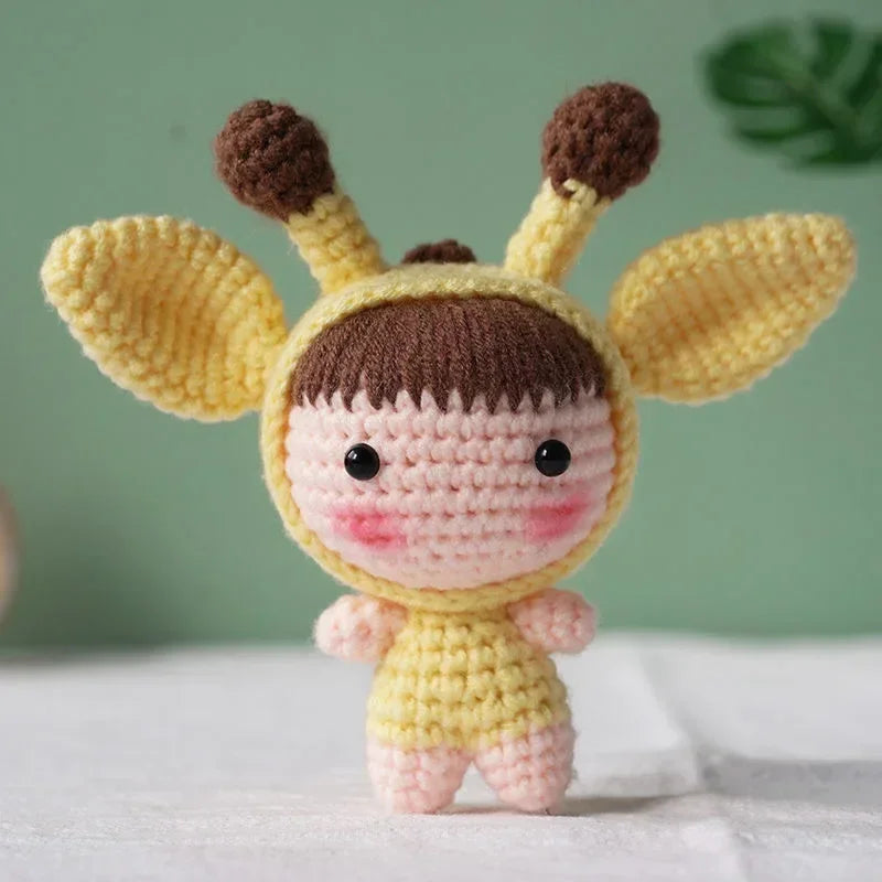 A handmade crochet doll kit featuring a yellow body, pink face, and brown ears with black eyes.