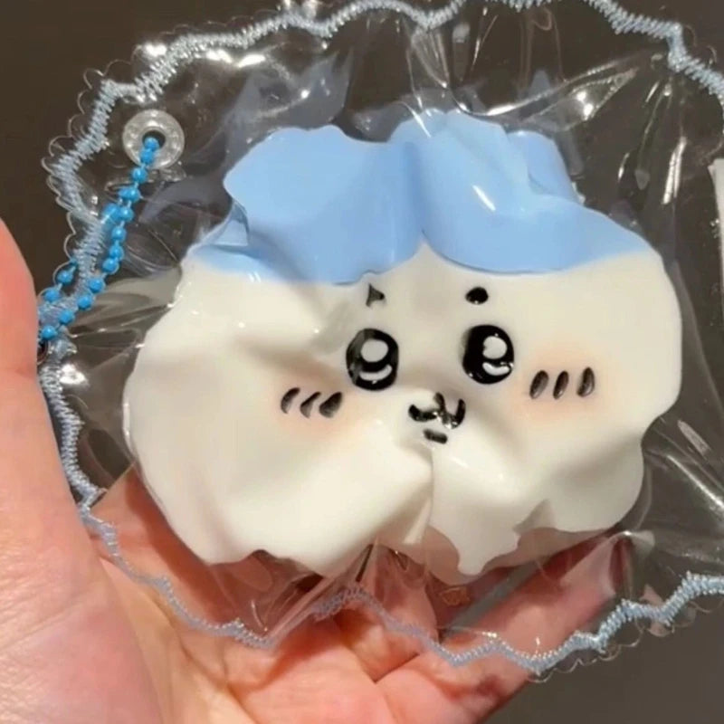 A white squishy toy shaped like a fluffy cloud with black facial features is sealed in clear plastic packaging.
