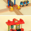 A wooden train track accessory set featuring a red station building and a blue train on a wooden track.