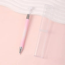 A pink refillable diamond picking pen with a rotating wax tip for nail art displayed on a light pink background.