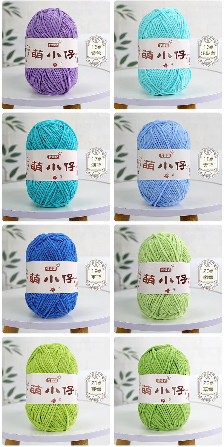 A collection of soft chenille yarn balls in various shades of purple, teal, blue, and green, displayed against a white backgr