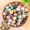 A bowl filled with colorful round silicone beads for jewelry making in various shades of pink, green, blue, and black.