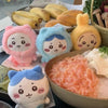 A collection of adorable Usagi Hachiware plush keychains in pink, blue, and yellow, displayed next to a bowl of pink and whit
