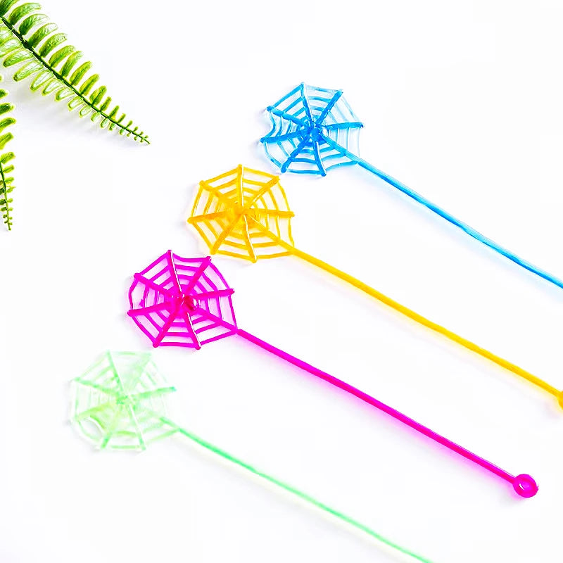 Colorful stretchy spider web toys in blue, yellow, pink, and green on a white background.