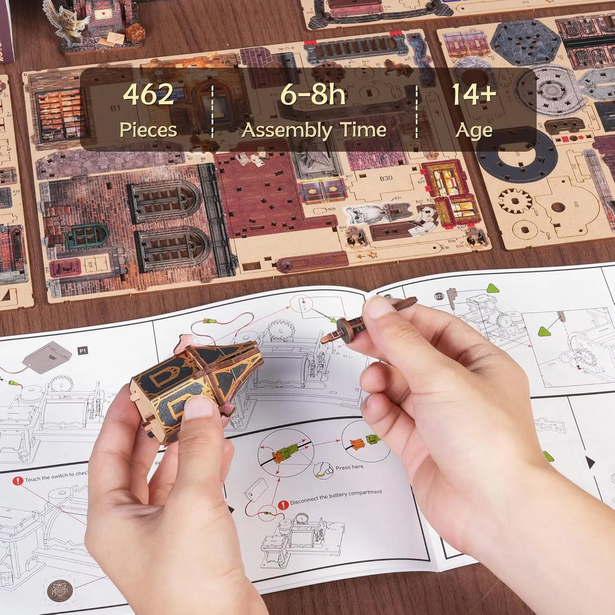Hands assemble a wooden miniature house kit puzzle featuring an illuminated owl post office and furniture.