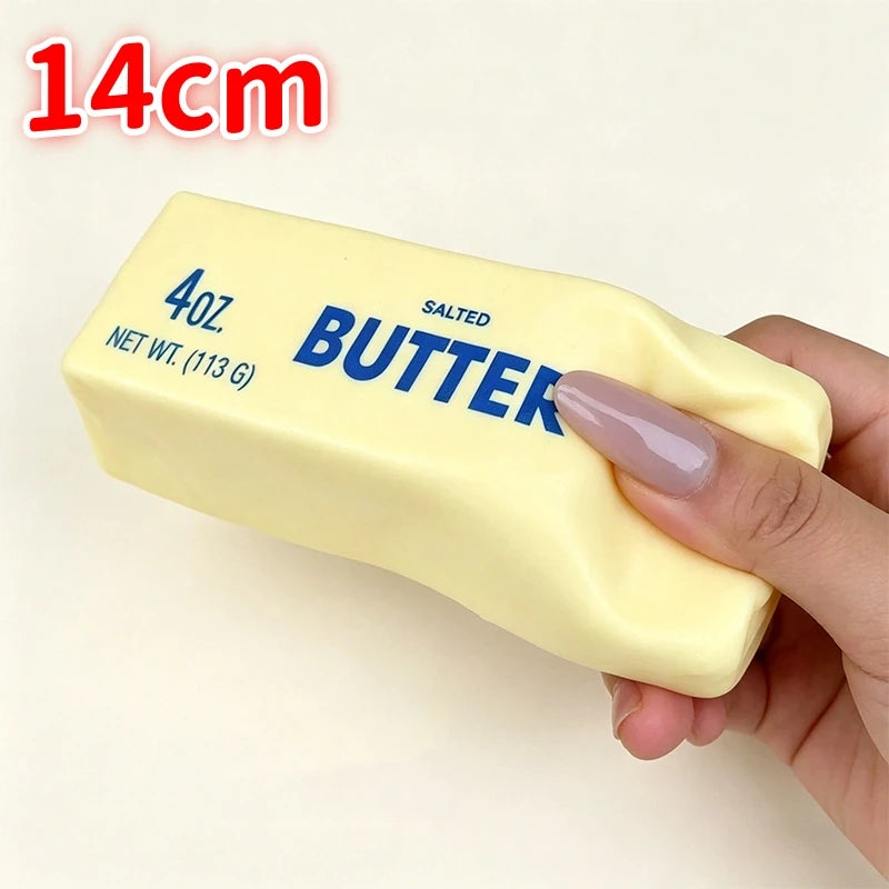 A hand holds a yellow salted butter stick fidget toy labeled 4oz net wt 113g