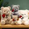 A collection of three plush teddy bears in various shades of gray and white, some holding red roses.