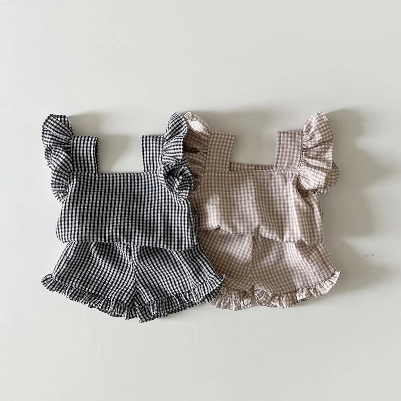 A set of baby girl ruffle top and shorts in black and white gingham and light pink gingham.