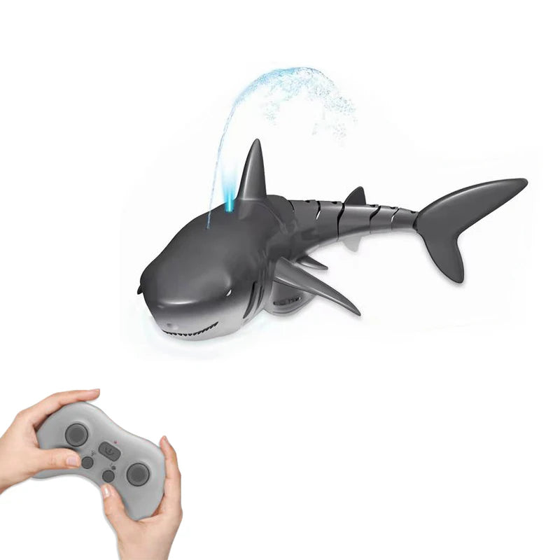 A gray swimming shark toy is shown in mid-air with water splashing around it, next to a hand holding a controller.