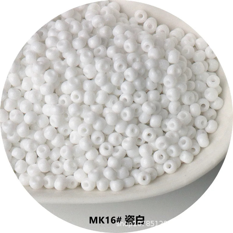 A pile of small, white, spherical electroplated metallic glass beads for jewelry and crafting.