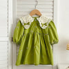 A lime green cotton party dress for girls featuring lace collar details and embroidered accents, hanging on a wooden hanger.