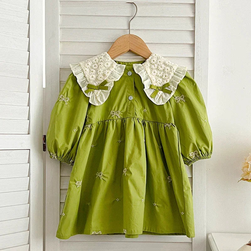 A lime green cotton party dress for girls featuring lace collar details and embroidered accents, hanging on a wooden hanger.