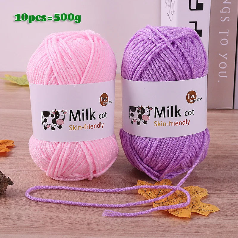 Two skeins of pink and purple silk yarn are displayed on a wooden surface with loose yarn strands.