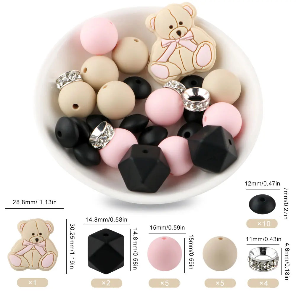 A white dish holds various pink and beige silicone beads shaped like teddy bears, round balls, and geometric pieces for jewel