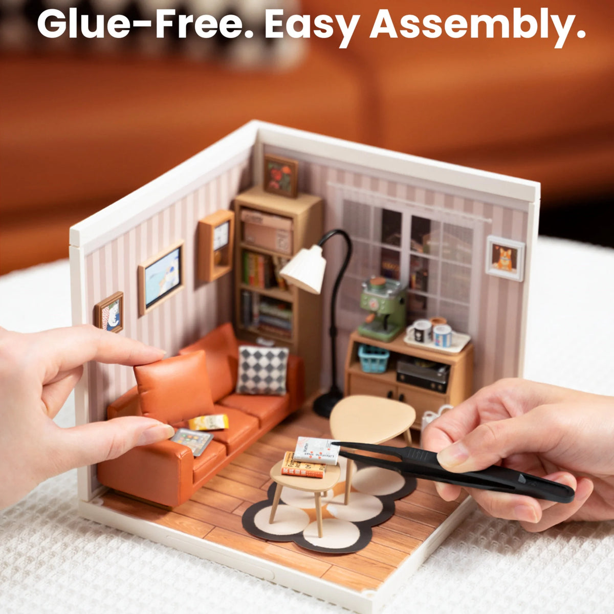 Hands assemble a wooden miniature house kit for a cozy living lounge with an LED light.