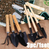 A set of three mini gardening tools with wooden handles and black blades resting on brown burlap fabric.