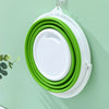 A stack of green and white collapsible buckets with lids hanging on a wall.