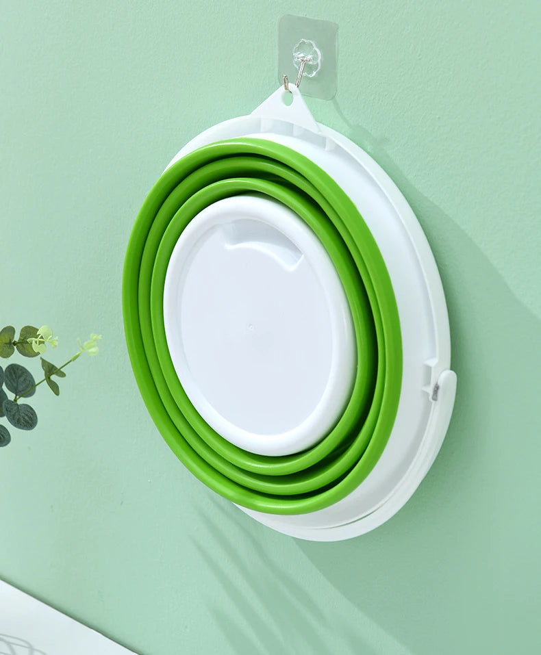 A stack of green and white collapsible buckets with lids hanging on a wall.