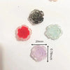 A collection of small, translucent resin flowers in shades of pink, red, and blue-green, displayed on a white background.