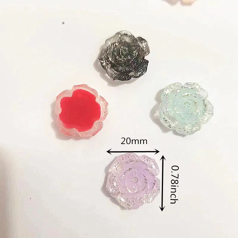 A collection of small, translucent resin flowers in shades of pink, red, and blue-green, displayed on a white background.