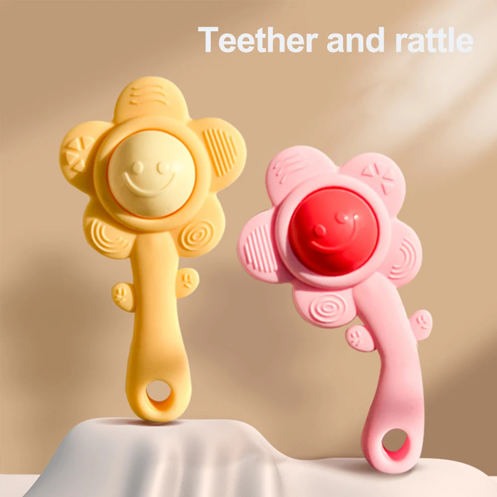 Two plastic teething rattles, one yellow and one pink, are displayed on a white surface.
