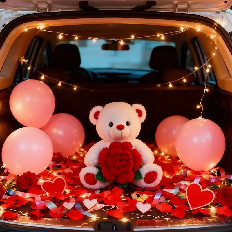 A plush bear holding a red rose surrounded by pink and red balloons inside a car