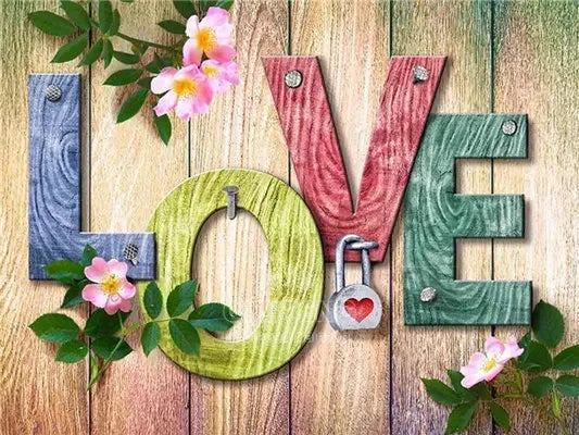 Wooden letters spelling LOVE decorated with pink flowers and green leaves